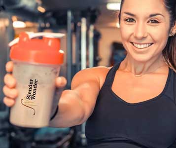 Woman holding Slender Wonder shaker at the gym smiling